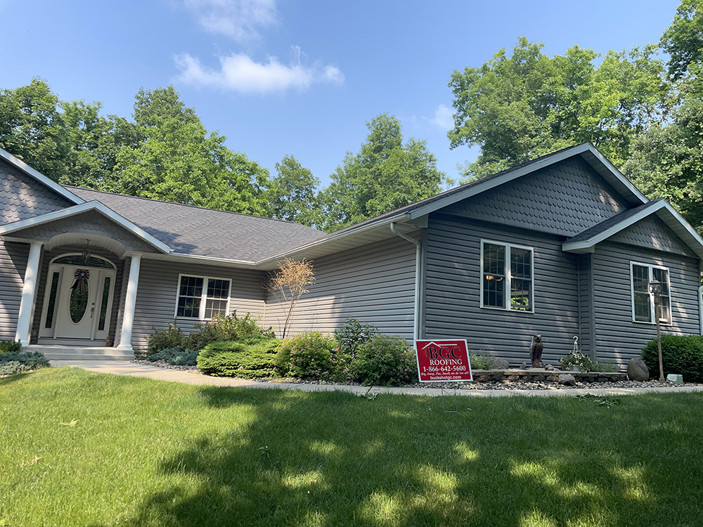 A well-maintained home with a new roof and siding in a green landscape