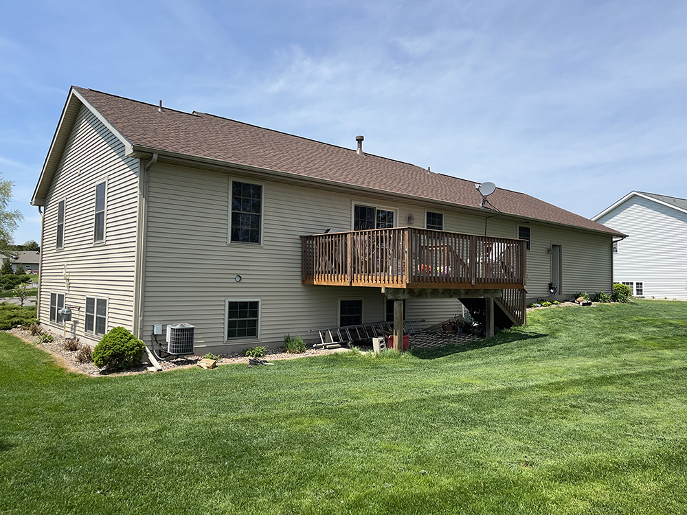 A well-maintained home with a deck and green lawn