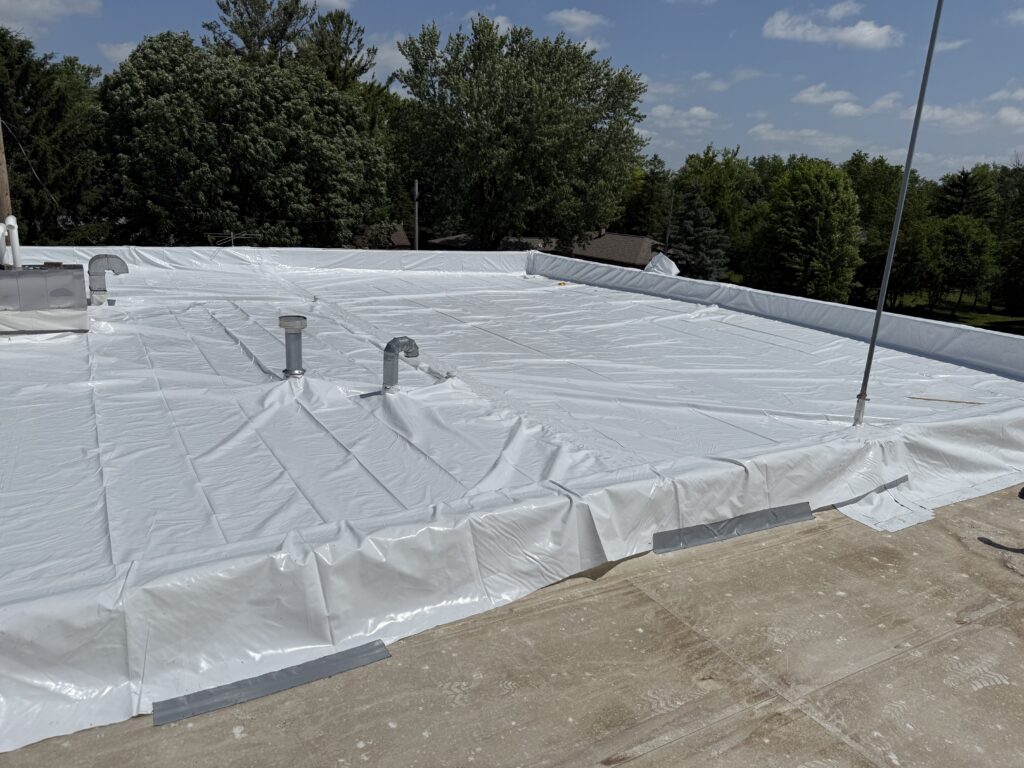 Low-slope commercial roof with a reflective membrane surface and rooftop penetrations
