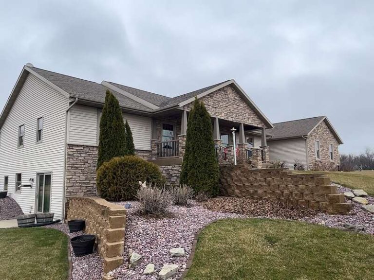A well-maintained home featuring a combination of stone and siding exterior with landscaped steps