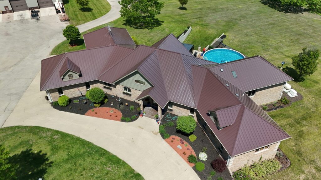 Aerial view of a residential home with a brown metal roof and landscaped yard