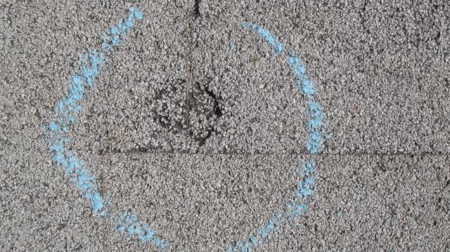 Hail strike circled in chalk on a shingle during a storm damage inspection