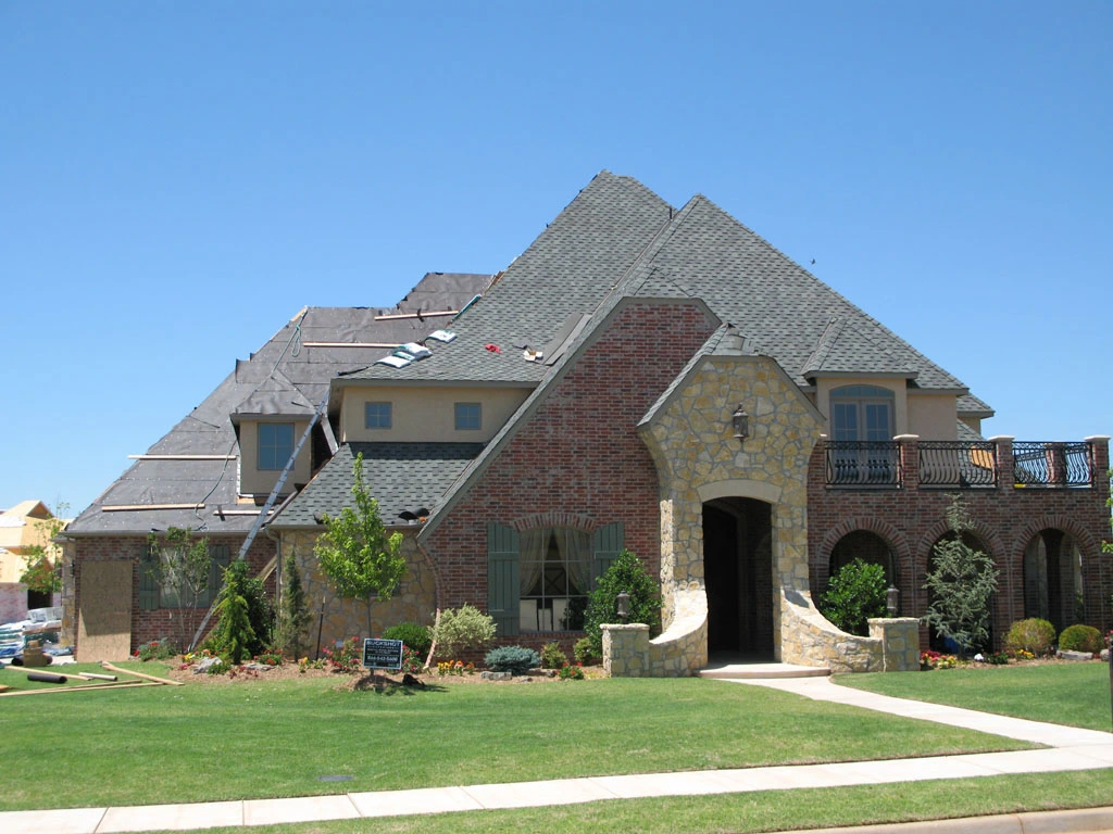 A large, multi-story home with a newly installed roof and brick exterior